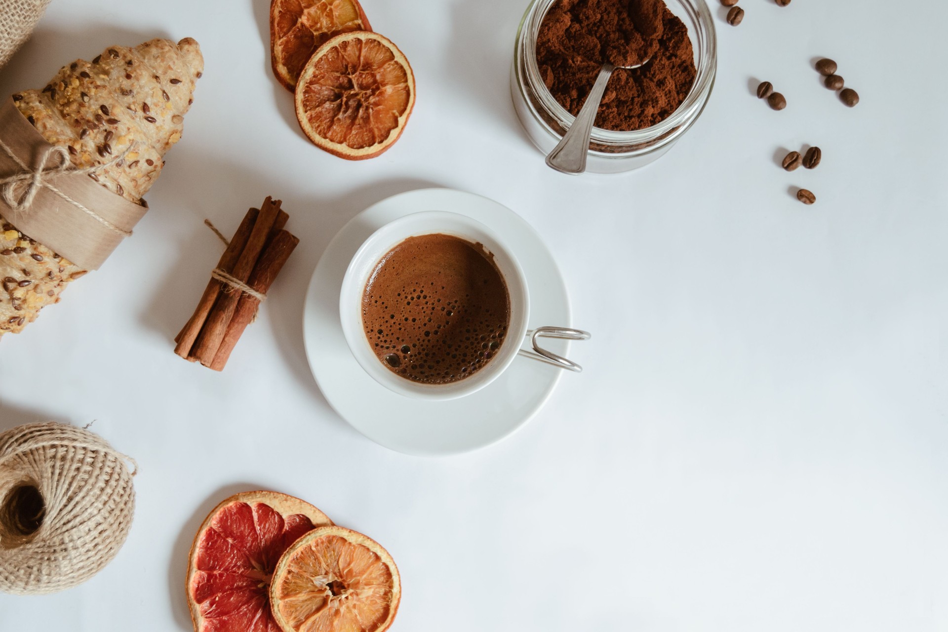 High angle shot of a coffee beside dried lemons, kifli, and roasted coffee beans